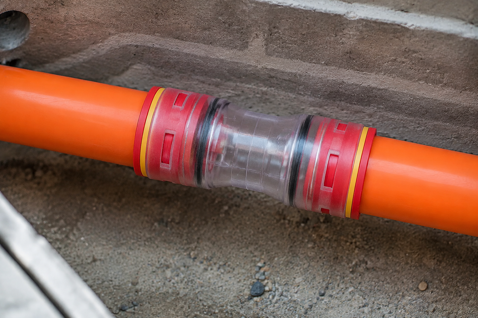 Close inspection view of an ANMASPC microduct straight connector joining orange HDPE microducts